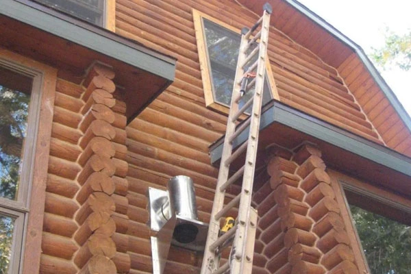 Safer Chimney LLC climbs the exterior wall to complete chimney repair on the home.